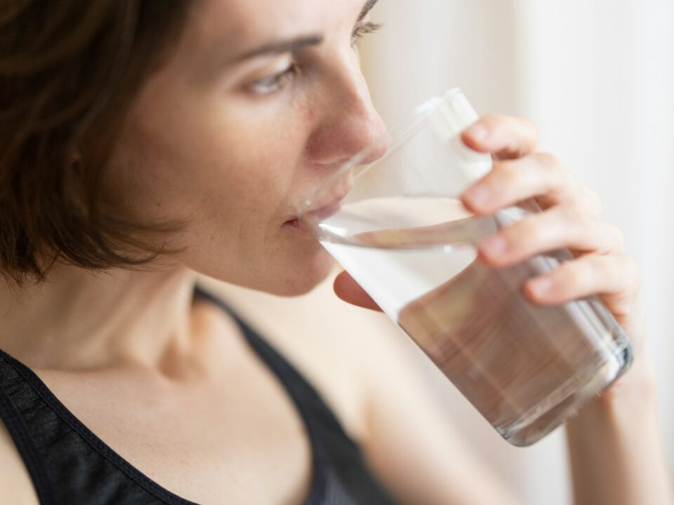 woman in black tank top drinking water
